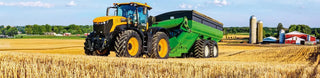 Yellow tractor with engine monitoring electronics pulling green grain cart in wheat field.