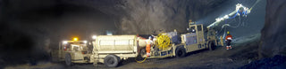 Mining and construction off-road vehicles working at night in a dusty environment.