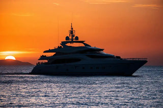 Luxury yacht silhouetted against a vibrant orange sunset sky